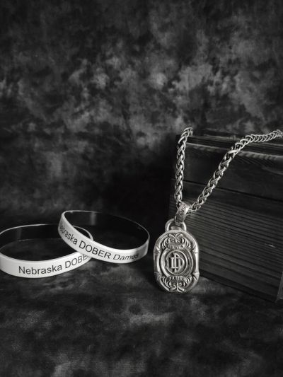 Black and white photo of Nebraska Dober wristbands and a detailed pendant necklace.