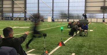 Indoor sports facility with coaches timing a sprinting athlete.