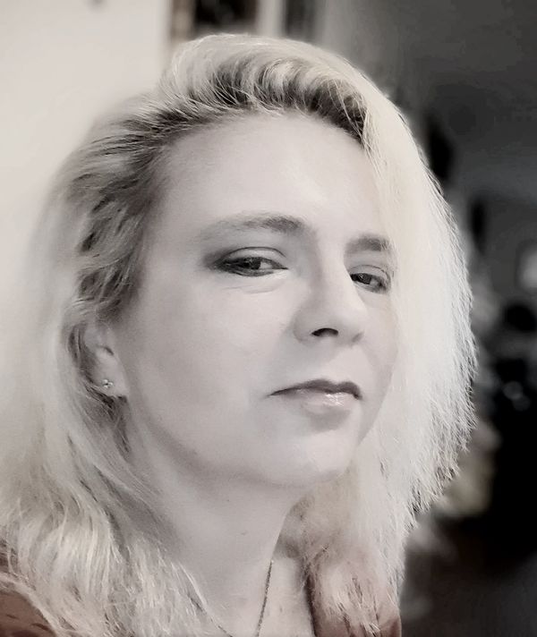 Close-up portrait of a confident woman with blonde hair and subtle makeup.