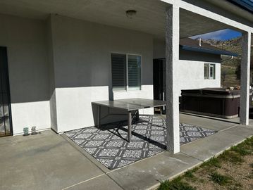 Empty patio with a table and rug under a covered porch.