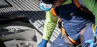 A worker in safety gear inspects an industrial floor area.