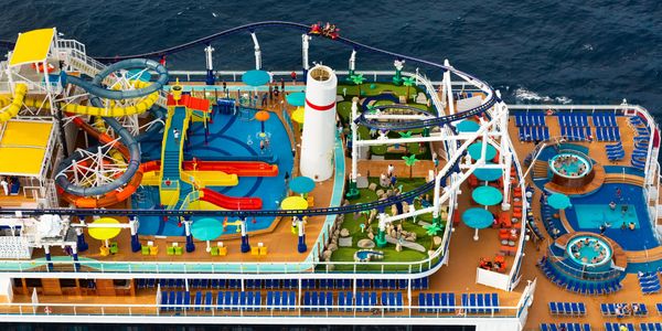 A cruise ship deck with water slides, pools, and a roller coaster.