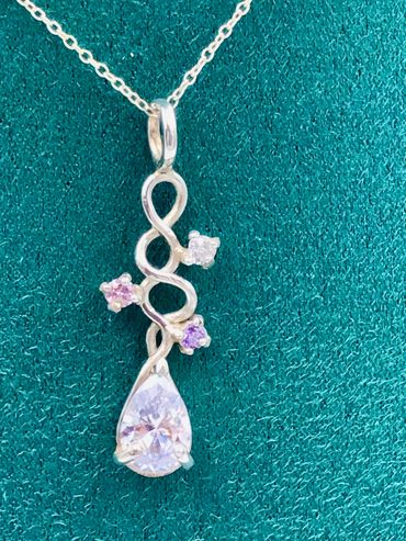 A pendant of interwoven silver wire set with three round and one pear shaped cubic zirconia stones.