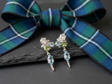 Elegant gemstone cluster earrings displayed with a blue and green plaid bow.