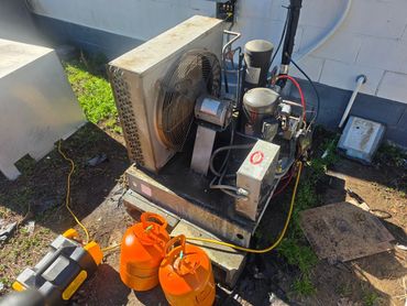 Outdoor HVAC compressor unit with refrigerant tanks and tools.