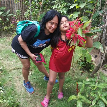 Woman and child posing in a garden with colorful plants.