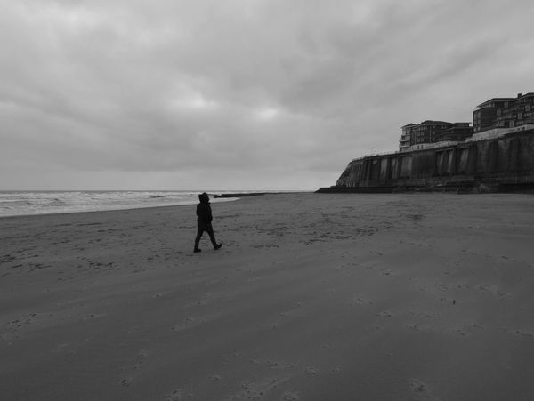 Solitary man walking on the wide beach