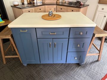 Blue kitchen island with white countertop and stools.