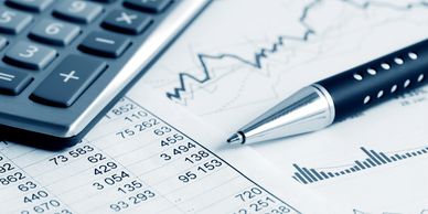 Calculator and pen on financial documents with charts and numbers.