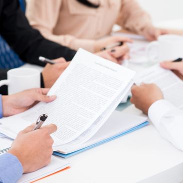 People reviewing documents and taking notes at a meeting.