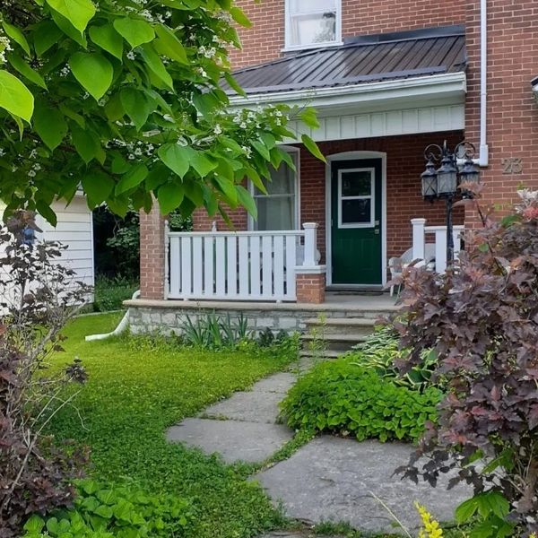 Cozy brick house with green door and lush garden.