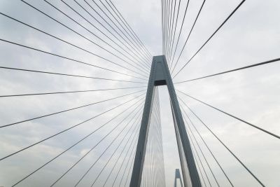 A modern cable-stayed bridge with a cloudy sky background.
