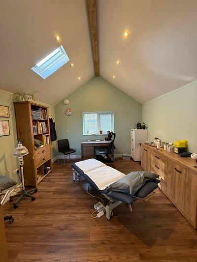 A cozy therapy or massage room with wooden furniture and soft lighting.