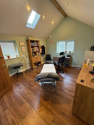 Well-organized therapy or treatment room with wooden floors and natural light.