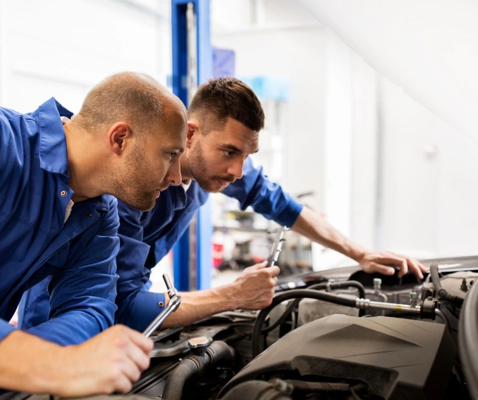 Two men looking at a car's engine. 