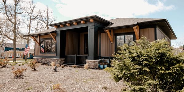 Modern brown house with black accents and American flags.