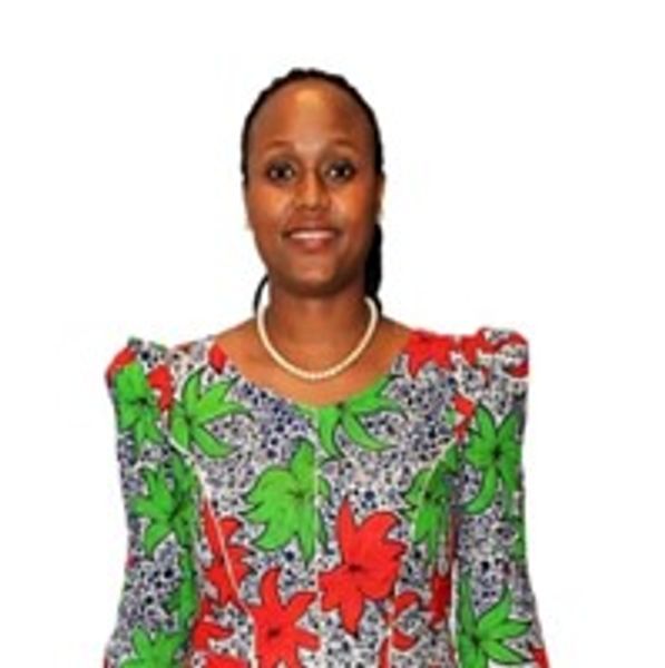 Woman wearing a colorful floral dress with red and green leaves.