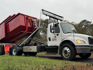 White Ameritex Dumpster truck with red roll-off container in action.