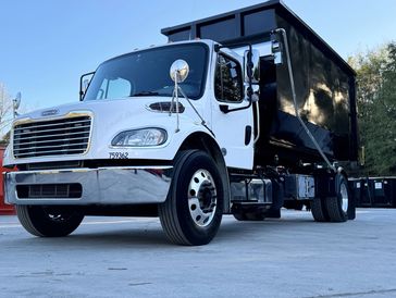 Freightliner hooklift truck with mounted black dumpster for hauling service, Truck left