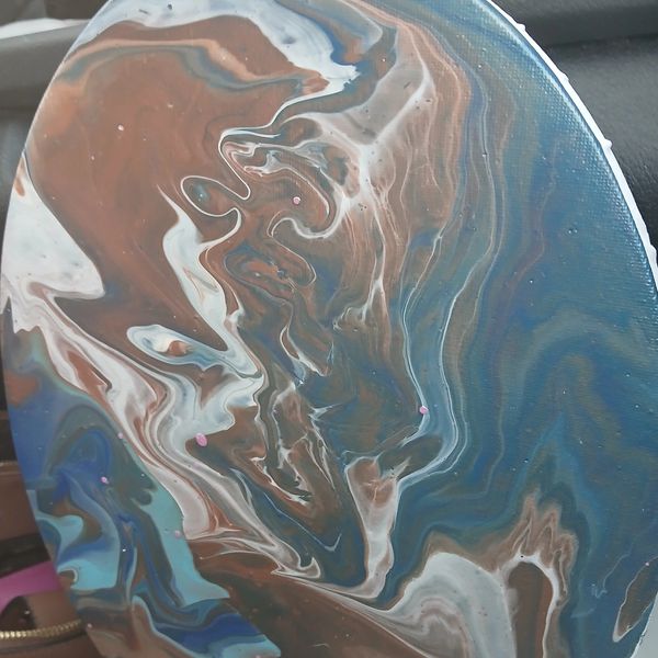 Abstract fluid art painting with swirling blues, browns, and whites on a round canvas.