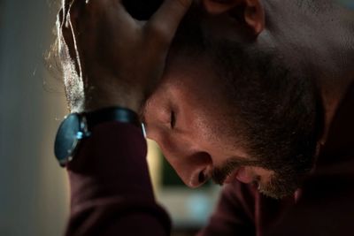 Close up of man eyes closed with his hand on his forehead