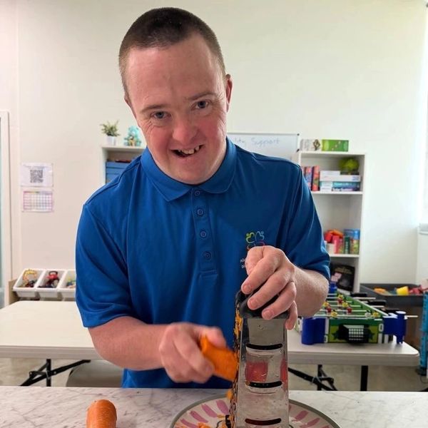 down syndrome man grating carrot