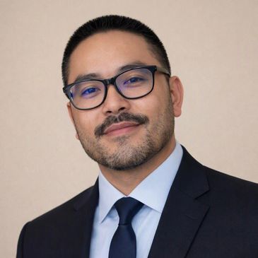 Man in a suit wearing glasses and smiling.