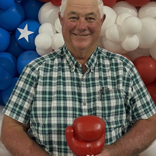 Smiling man holding red boxing gloves.