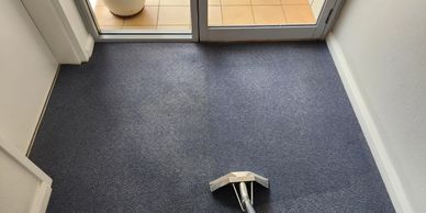 Carpet cleaning in progress near a glass door.