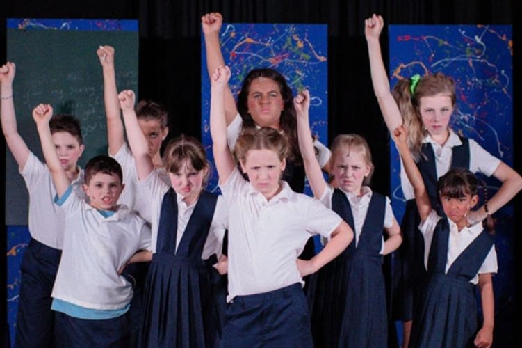 Children in Navy Blue & White School Uniforms, one hand on hip, one hand punching the air: Revolting