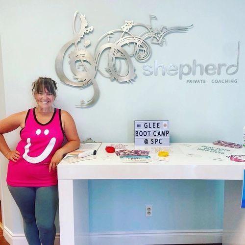 Creative Director & Owner, Lauren Shepherd, standing in lobby under studio logo sign.