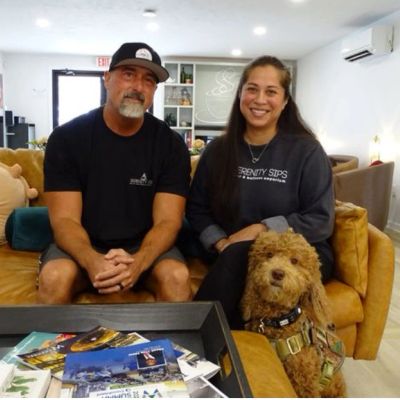 Man and woman sitting on a couch with a dog in a cozy living room.
