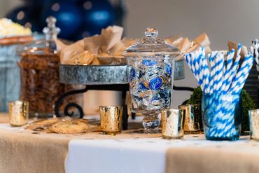 A sweet and salty snack station with cookies, candy, popcorn and flavored soda with striped straws