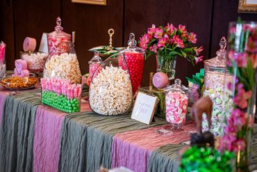 Colorful candy and popcorn display with pink flowers on a table for a bridal shower, engagement or bachelorette party.
