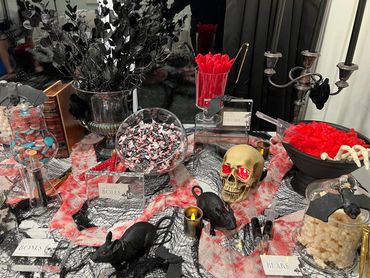 A spooky goth Halloween candy table with skulls, black rats, and eerie decorations.