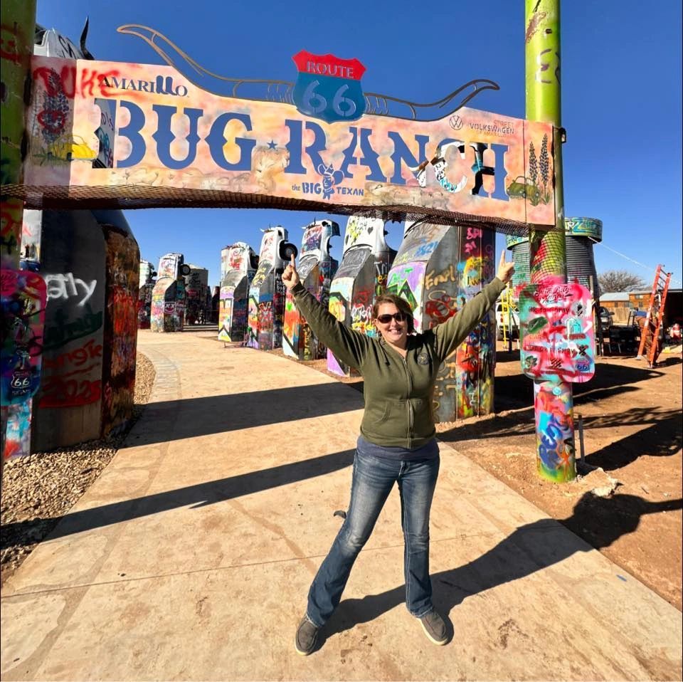 Person posing excitedly at the colorful Amarillo Bug Ranch entrance on Route 66.
