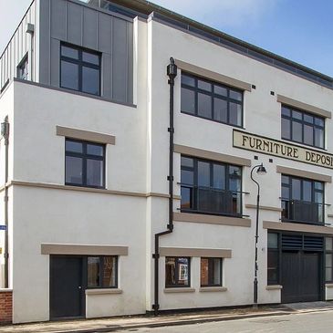 Modern white building with large windows and Furniture Deposit sign.