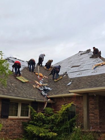Several workers repairing a roof on a cloudy day.