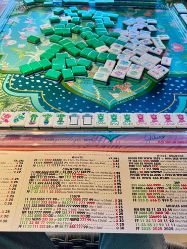 Mahjong game setup with colorful tiles and reference sheet on a vibrant table.