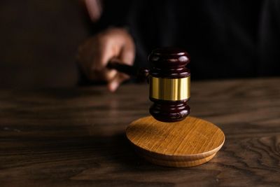 A judge's gavel striking a wooden sound block on a dark table.