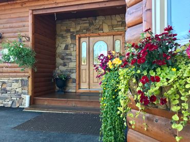 Front porch entrance with stone walls and vibrant flowers.