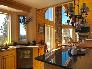 Cozy wooden cabin kitchen and dining area with large windows and natural light.