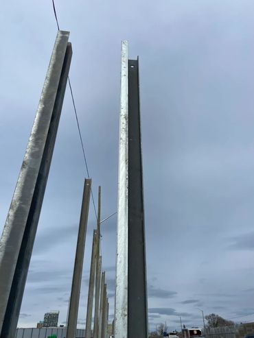 Tall metal poles stand in a line against a cloudy sky.