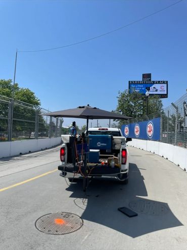 A pickup truck with equipment and umbrella parked on a race track.