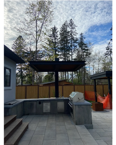 Modern outdoor kitchen with grill and sink under a canopy in a backyard.