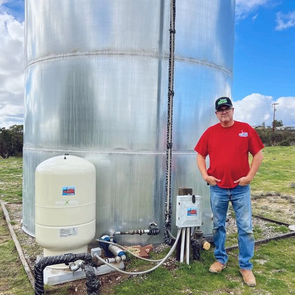 Man standing next to industrial equipment and water tank.