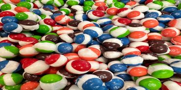 A pile of colorful, half-white M&M candies.
