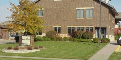 Outside view of office/building. Brown brick with green grass lawn. 
