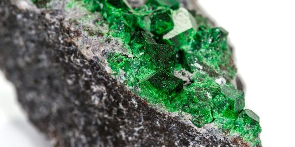 Two vibrant tsavorite with brilliant facets on a smooth surface.