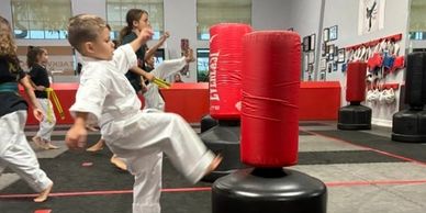 Children practicing martial arts with punching bags.